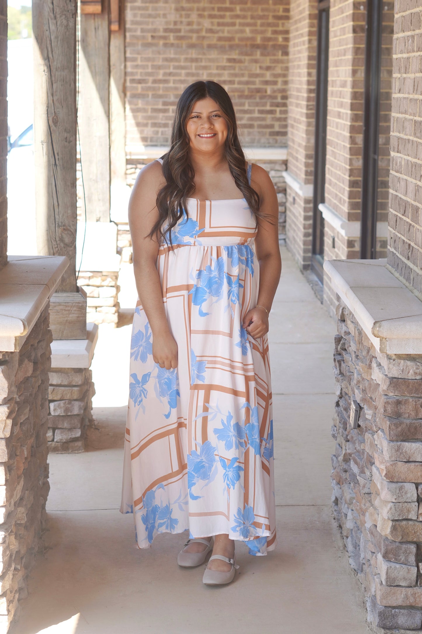 Women wearing a blue floral with. brown lines printed maxi dress, sleeveless, square neckline, flowy fit. 