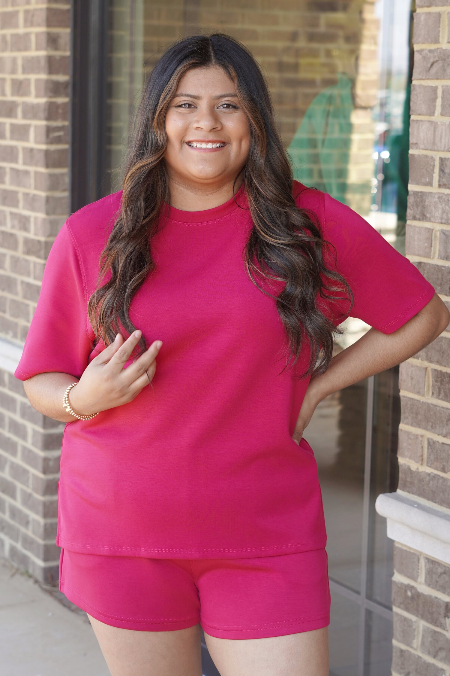 Woman wearing a pink oversized short-sleeve tee with side slits, crew neckline, paired with matching pink shorts. 