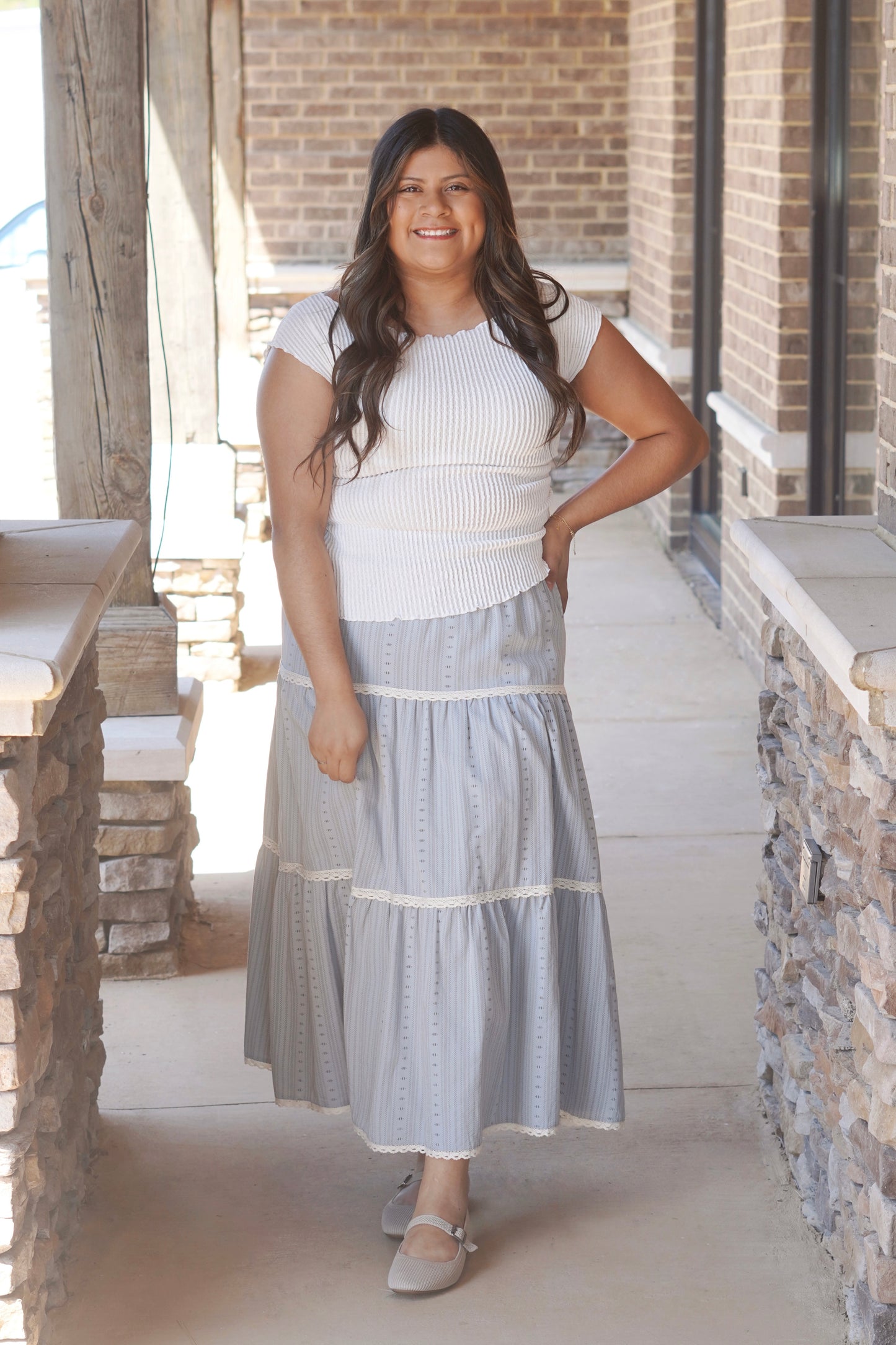 Women wearing a grey maxi skirt, with a lace trim detail in each tiered.  