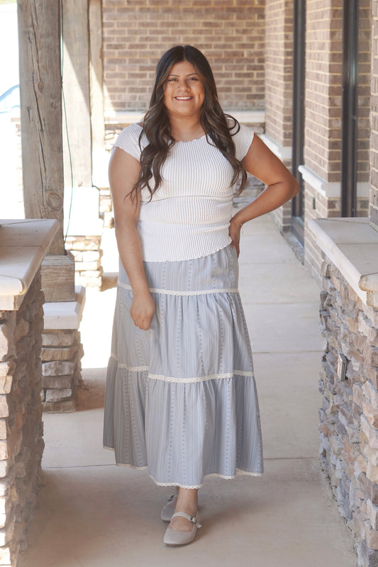 Women wearing a grey maxi skirt, with a lace trim detail in each tiered.  