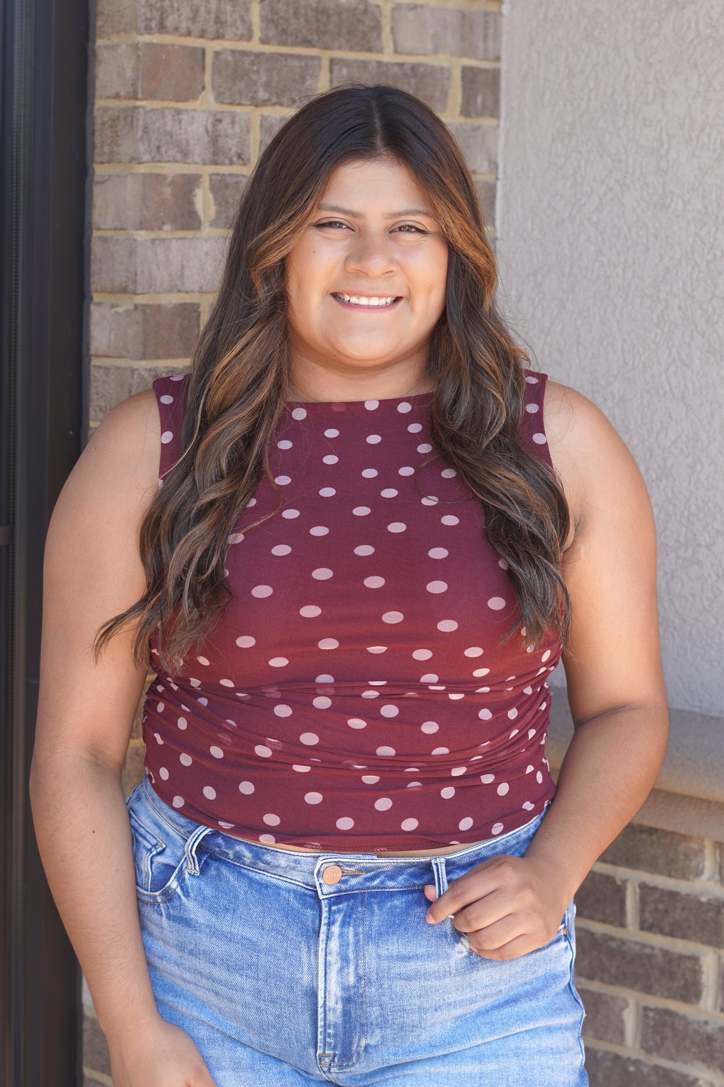 A matron tank top with pink polka dots and a smocked detail on the sides. 