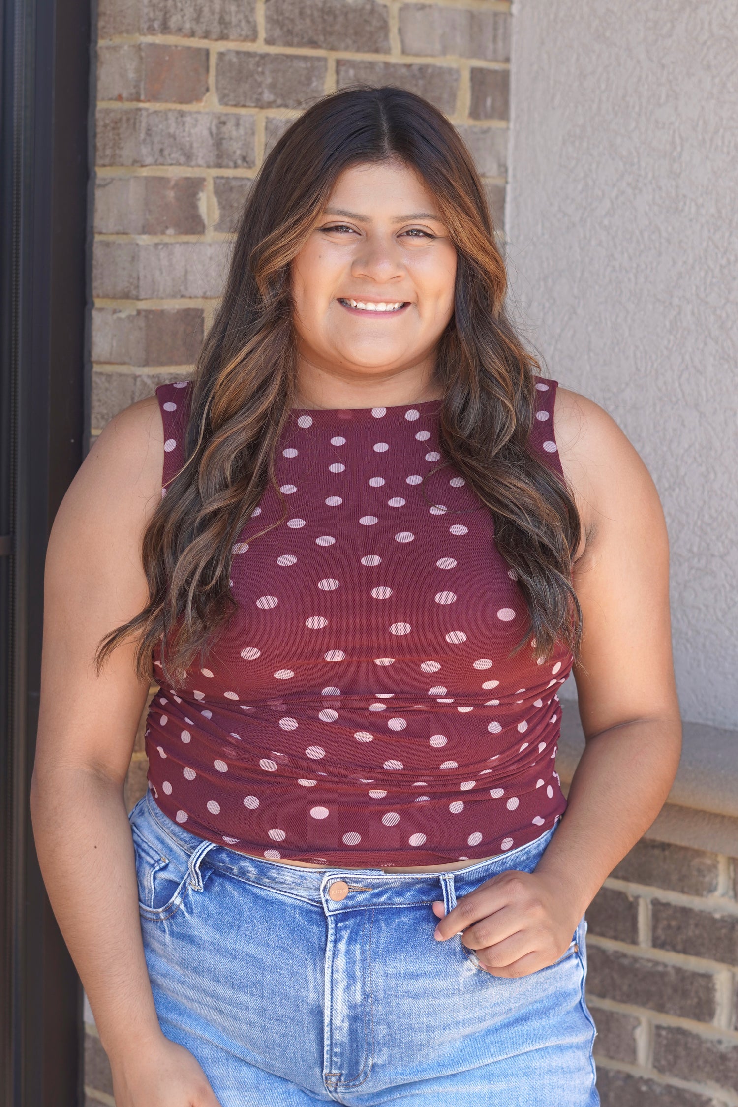 A matron tank top with pink polka dots and a smocked detail on the sides. 