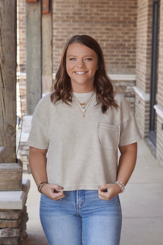 Woman wearing cropped a cream colored Ribbed Short Sleeve pocket Tee with a Round Neckline and Short Sleeves paired with jeans
