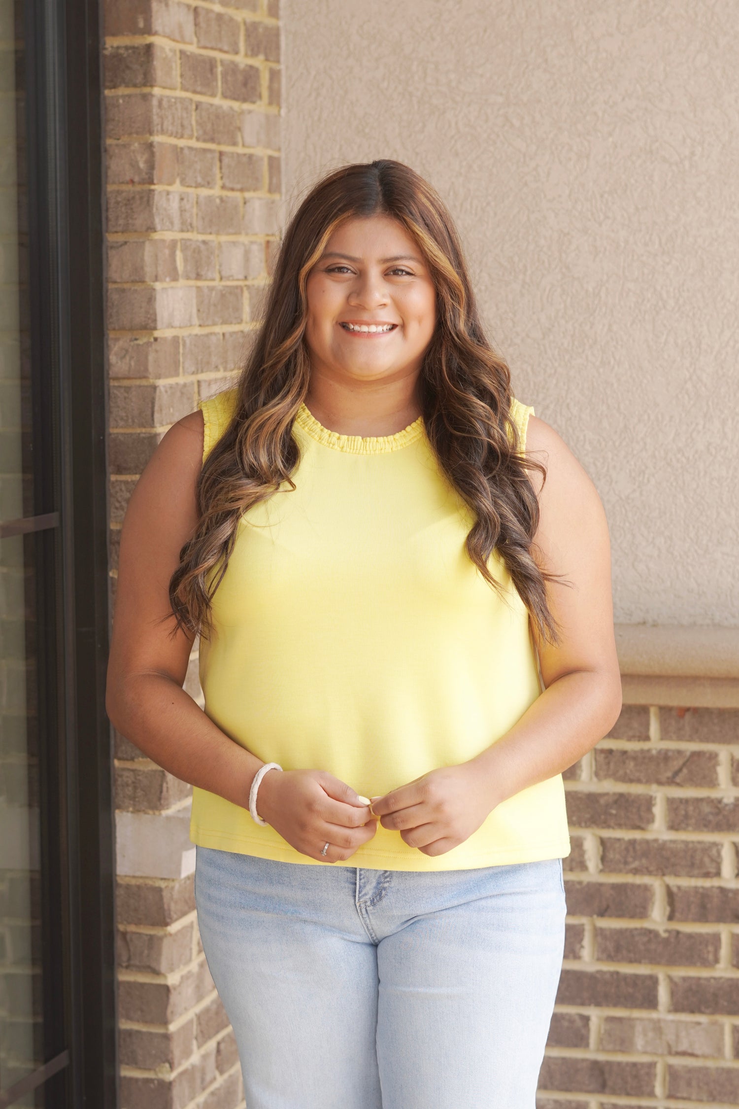 Women wearing a yellow tank top that has a ruffle trim in the neckline as well as the sleeves, sleeveless, round neckline.