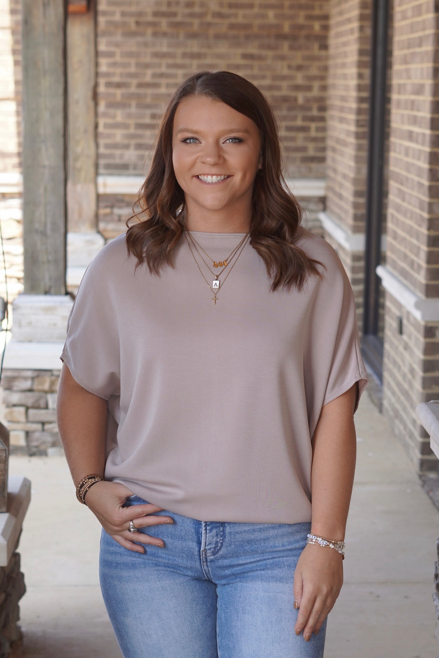 Woman wearing beige short sleeve blouse paired with light wash blue jeans