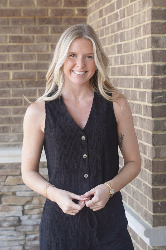 Women wearing a black texture v-neck vest, buttons going down the middl.