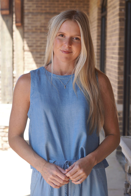 Women wearing a sleeveless blue top with a round neckline. 