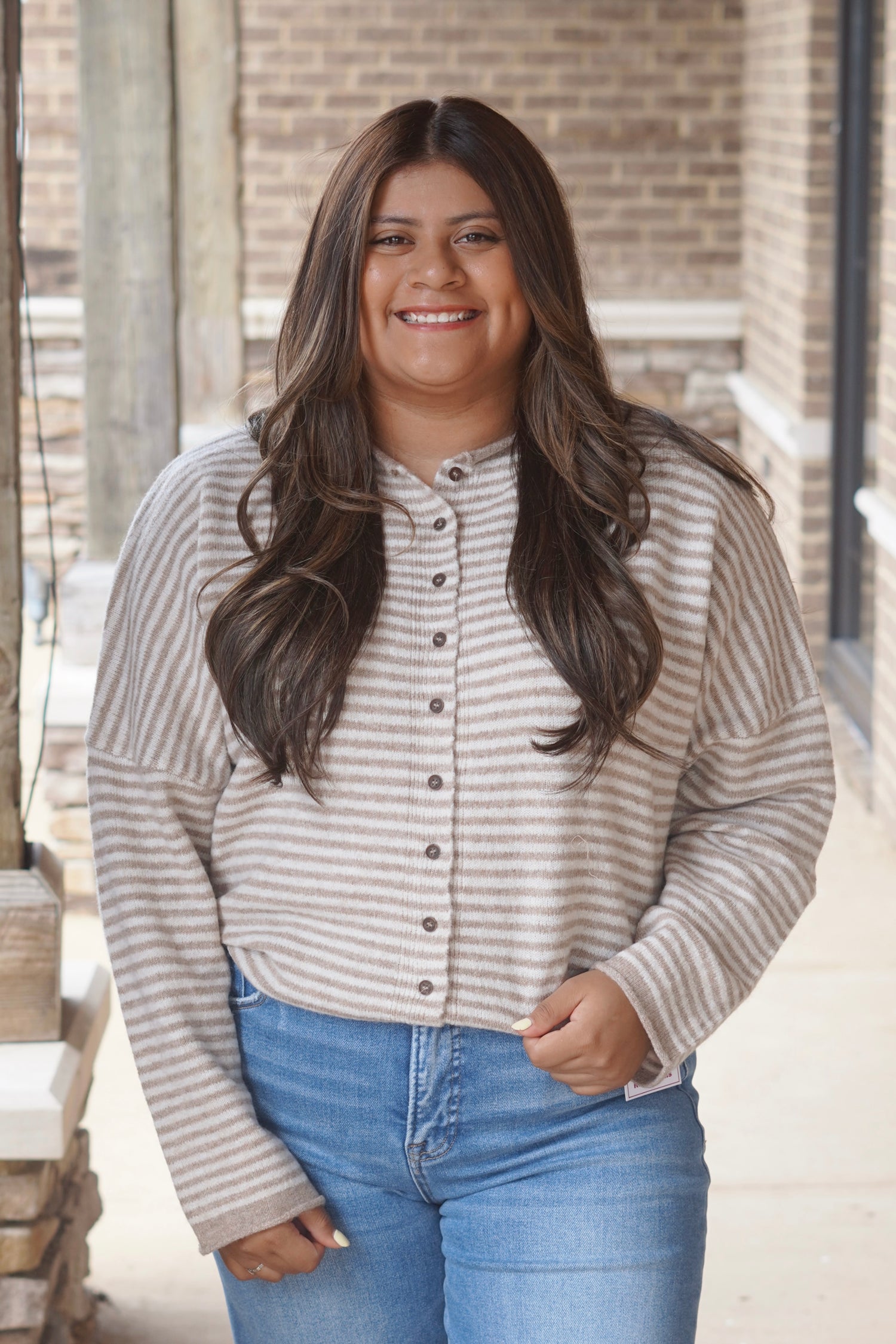 Women. wearing a taupe and ivory striped sweater, button down, round neckline