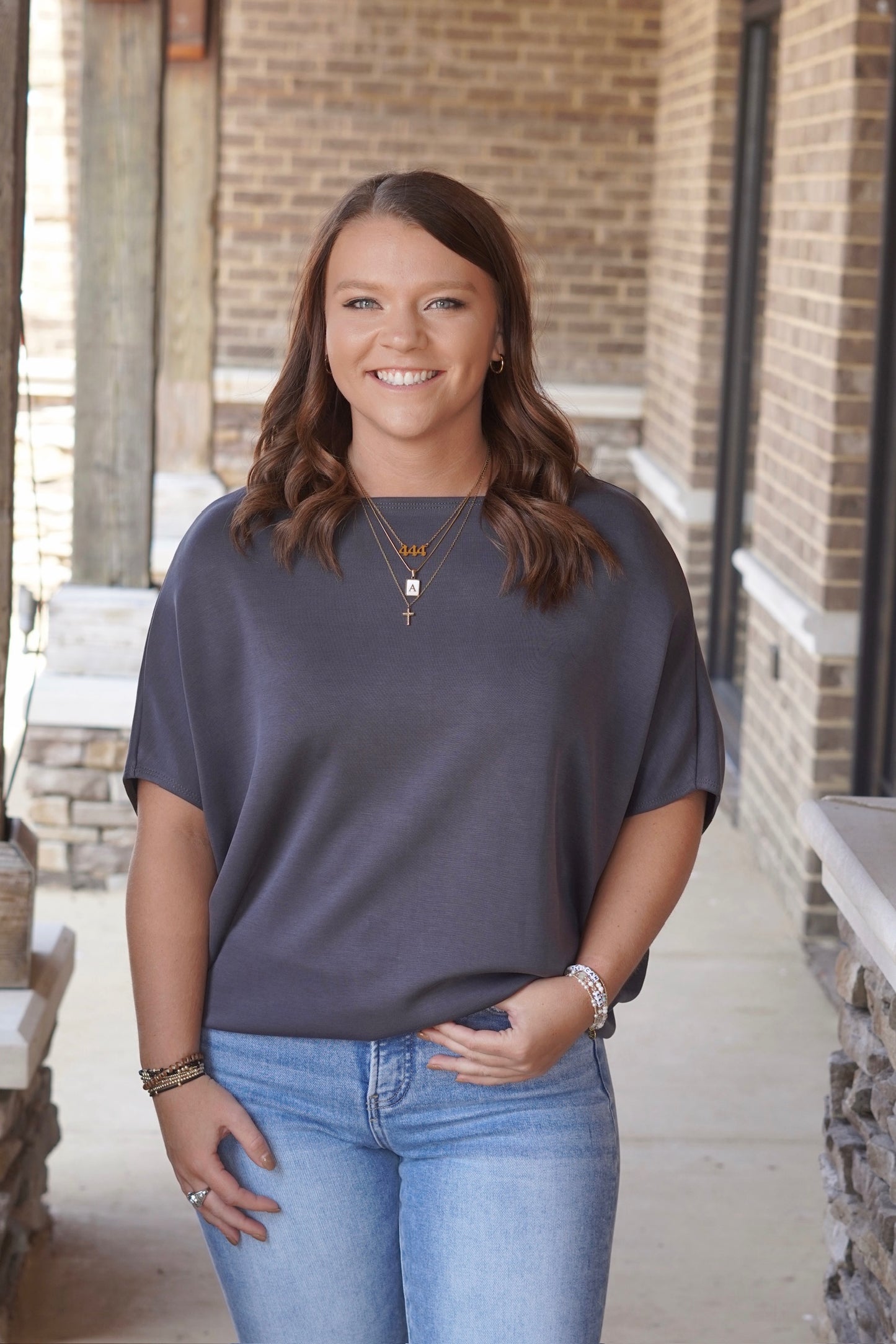 Woman wearing grey short sleeve blouse paired with light wash blue jeans