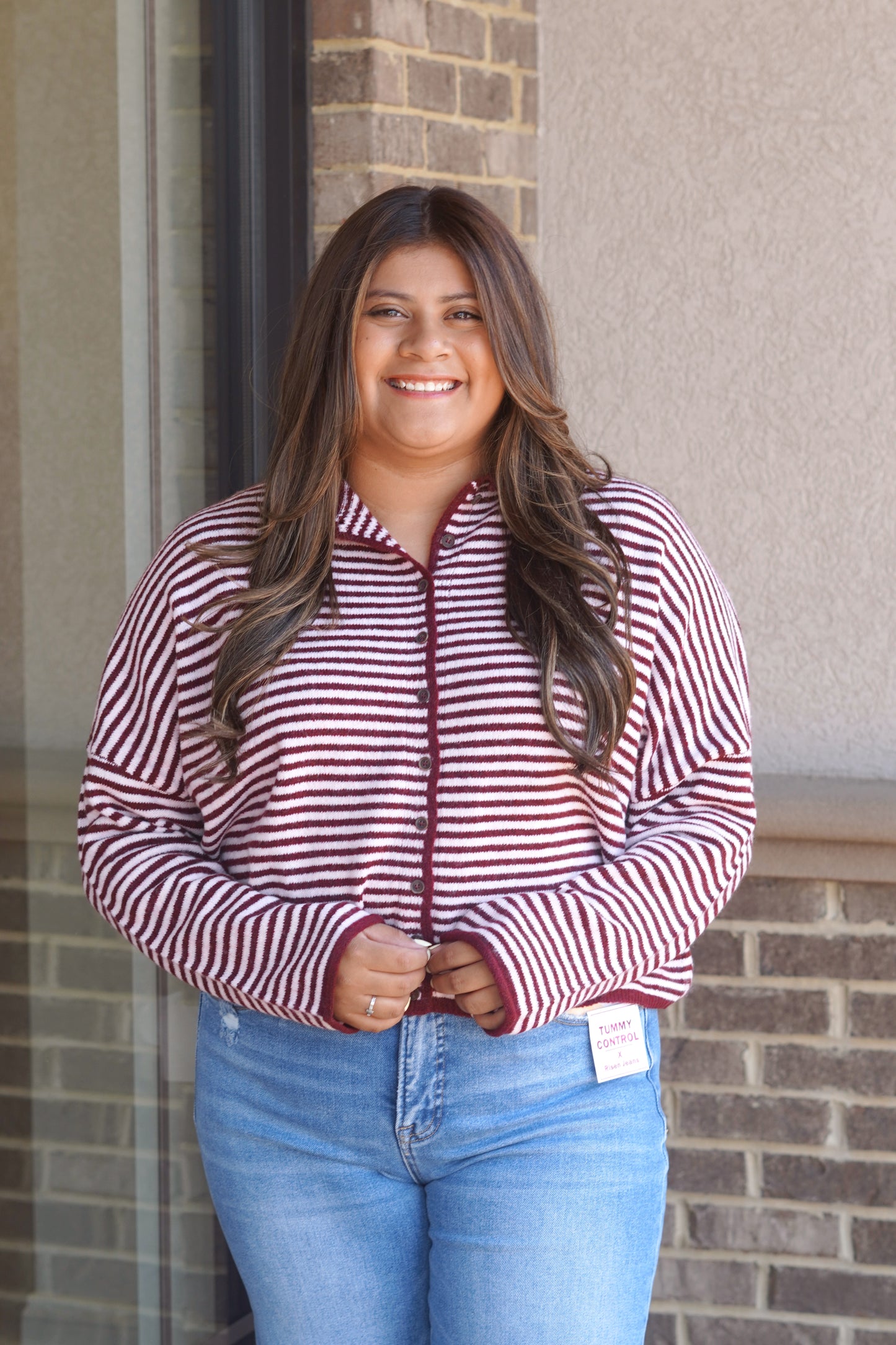 Women. wearing a burgundy and light red striped sweater, button down, round neckline