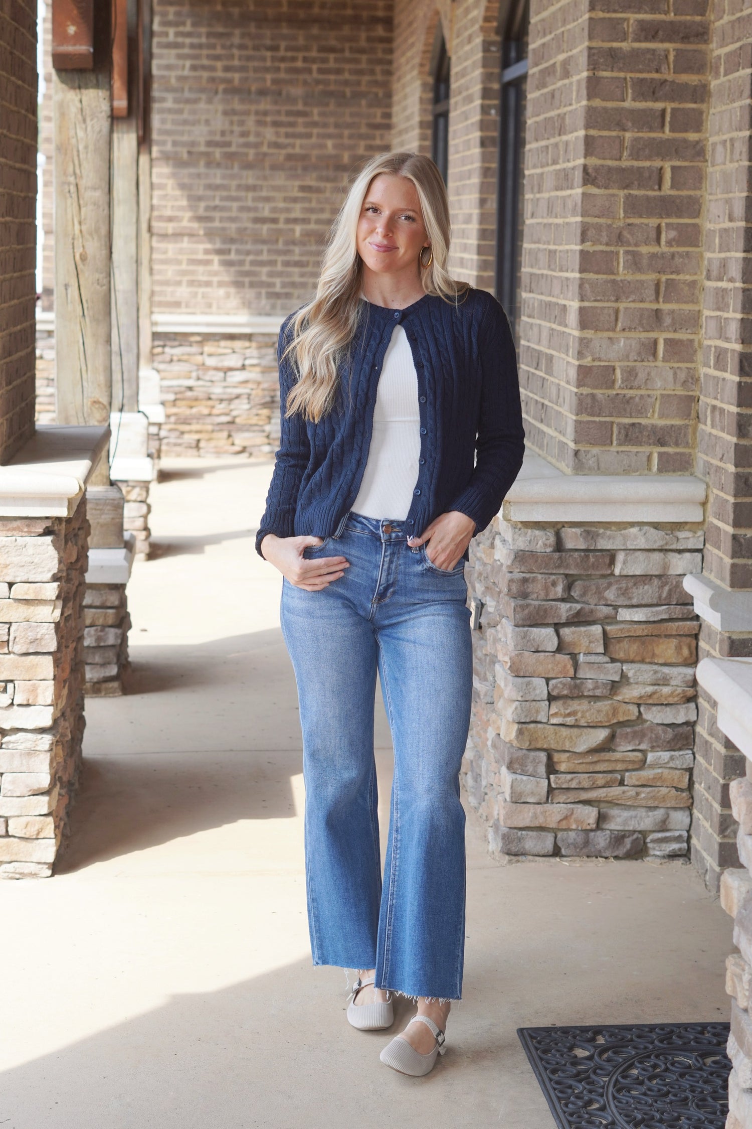 Women wearing a Navy Cable Knit Cardigan, style with a white top underneath and a pair of jeans 