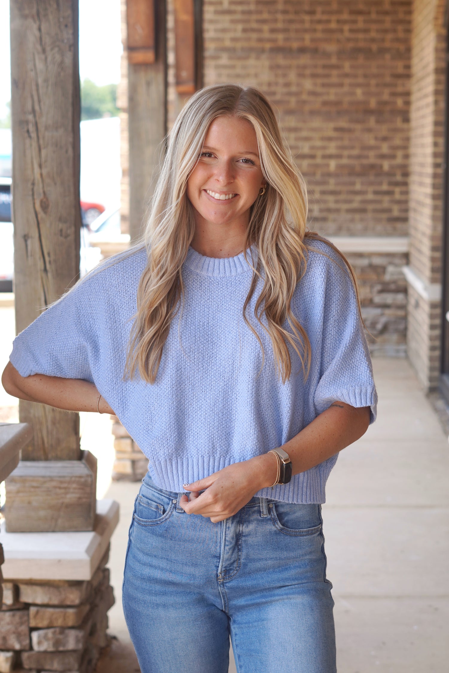 Women wearing a blue top, knit material, short sleeves, crew neckline. 