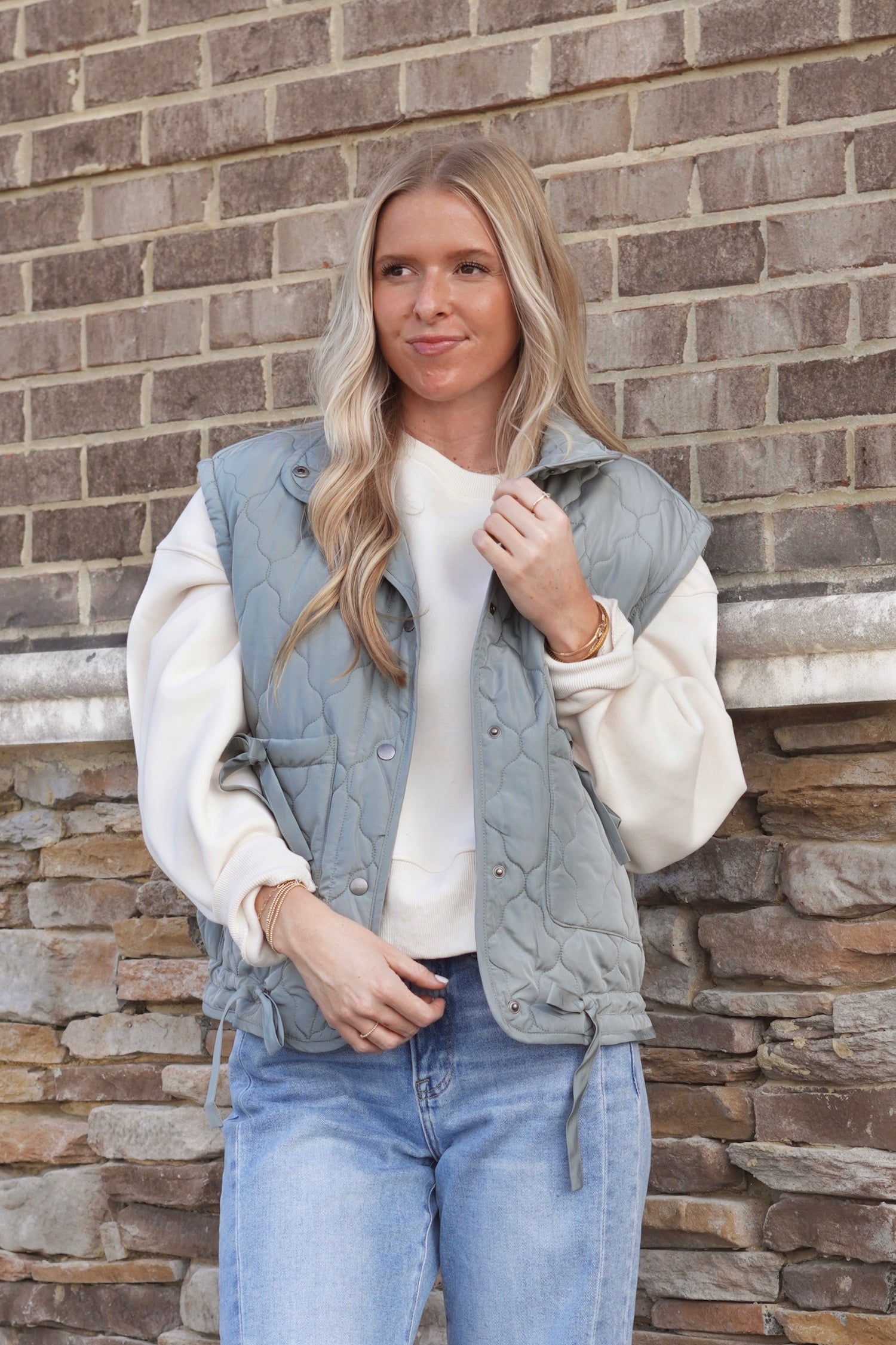 Women wearing a Sage Bow Detail Quilted Puffer Vest, Collar Neckline, Snap Button Down, Full Length, Pockets, style with a white crewneck and jeans. 