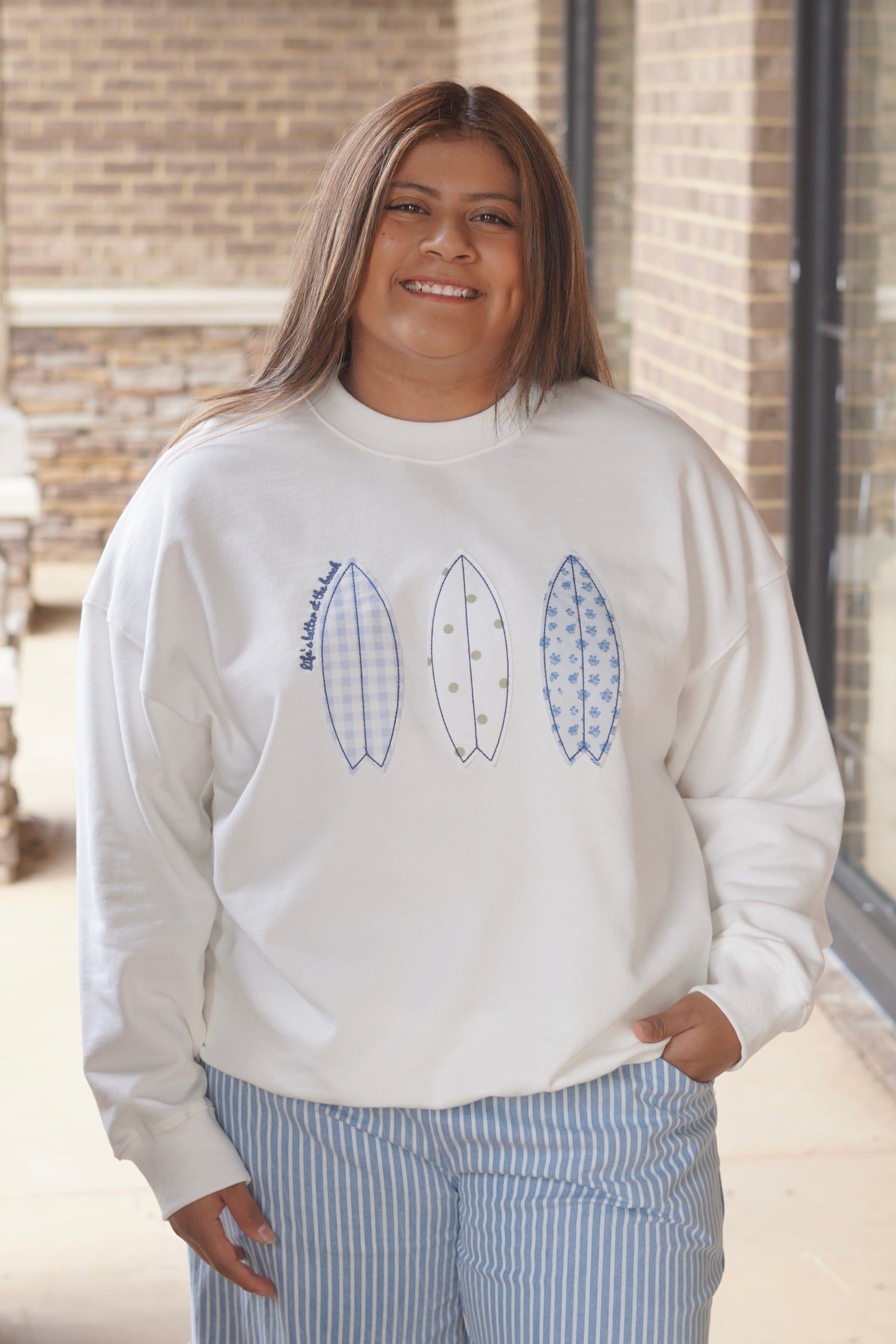 Women wearing a white sweatshirt with surfboard patches in different prints, crew neckline. 