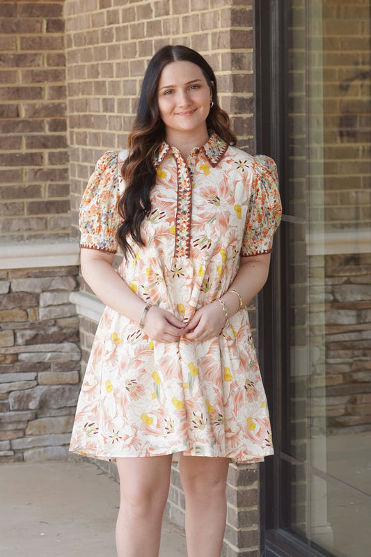 Women wearing a ivory floral print mini dress with short puff sleeves, and a collar neckline, flowy. 