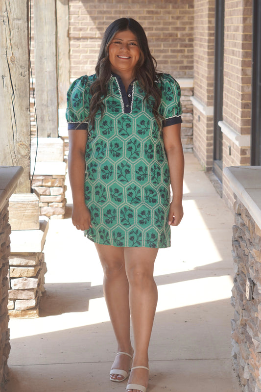 Women wearing a green short dress with navy floral pattern, lace detail, short puff sleeves and a collar neckline.