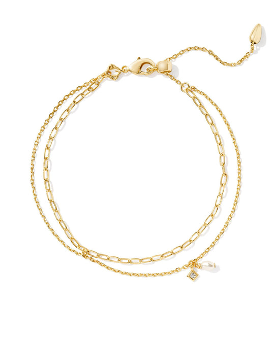 two strand gold bracelet and one strand has a crystal and pearl chram