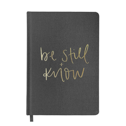 Black journal with gold lettering that says " be still and know"