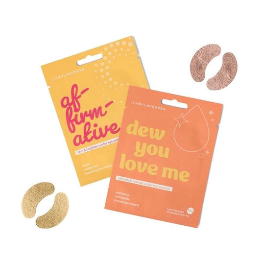 Two eye patch packaging packets, one yellow reading 'af-firm-ative' and one orange reading 'dew you love me', with two gold-toned eye patches and two rose gold-toned eye patches placed around them on a display. 