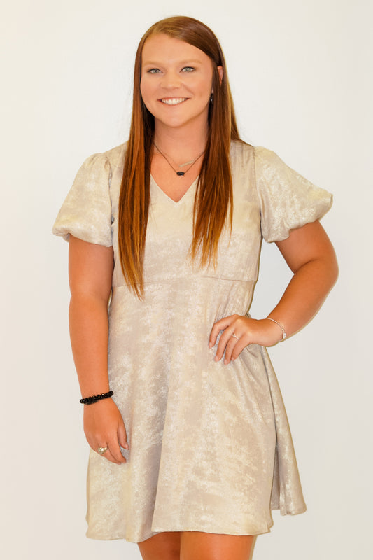 Samantha Shimmer Puff Sleeve Dress V-Neckline Short Puff Sleeves Relaxed Fit Knee Length Gold Shimmery Color 100% Polyester Lining, 100% Polyester Model is wearing a size small. 