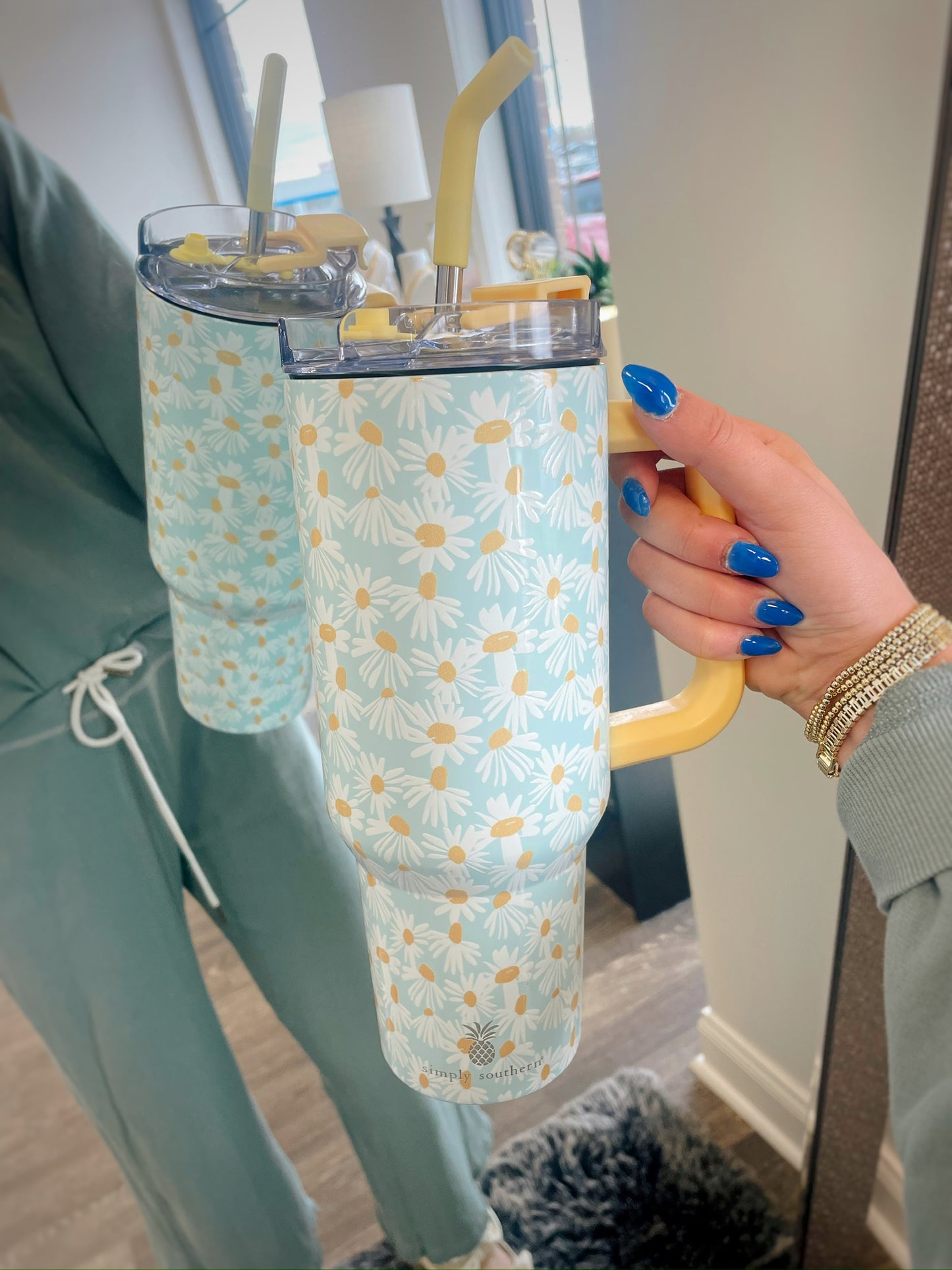 blue tumbler with yellow and white daisies printed on it and a yellow handle