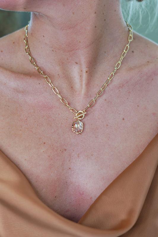gold chain link necklace with a pink iridescent abalone stone. toggle closure