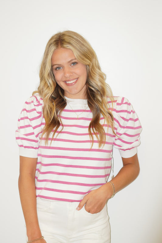        This Corlie Candy Striped shirt is so cute for your next Summer outing! The cute striped detail and puff sleeves make this top so unique. Pair it with our Lola white Summer Shorts and sandals or sneakers!     Corlie Candy Striped Shirt Round Neckline Full Length Puff Sleeve  White and Pink Striped 50% Viscose, 28% Polyester, 22% Nylon