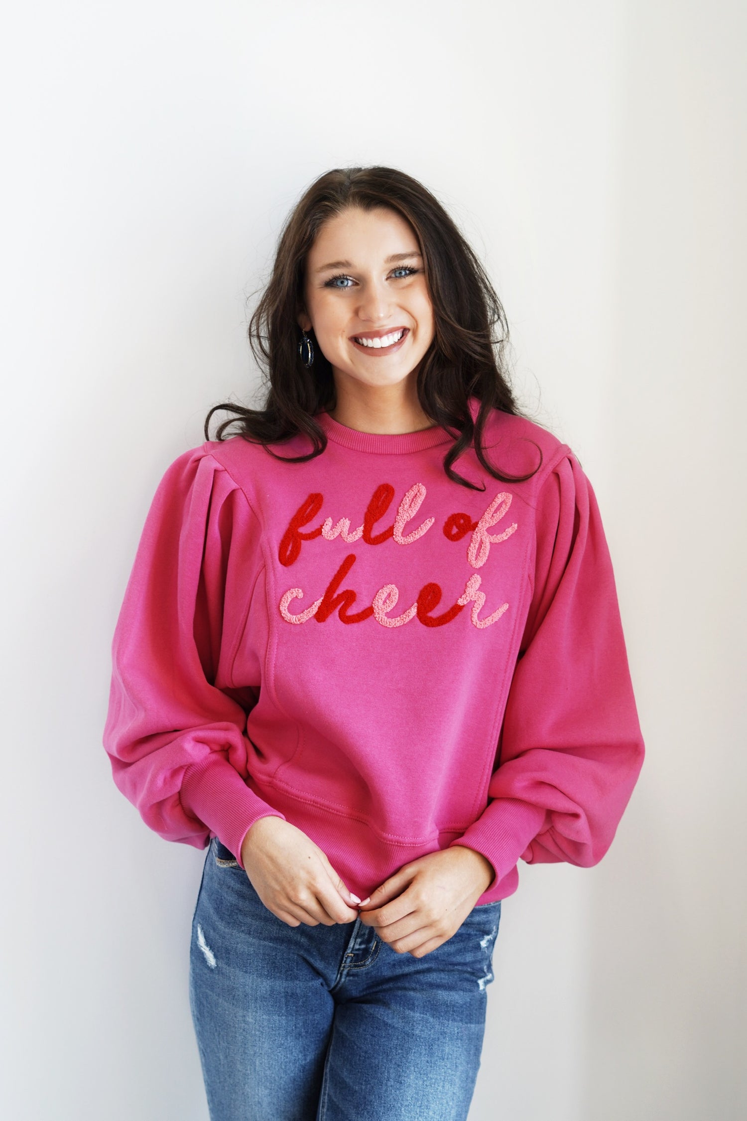 "Full of Cheer Pink Crew Neck Crew Neckline Long Cuffed Ribbed Hem Color: Pink Light Pink and Red Lettering that says "Full of Cheer" Relaxed Fit Full Length 60% Cotton, 40% Polyester