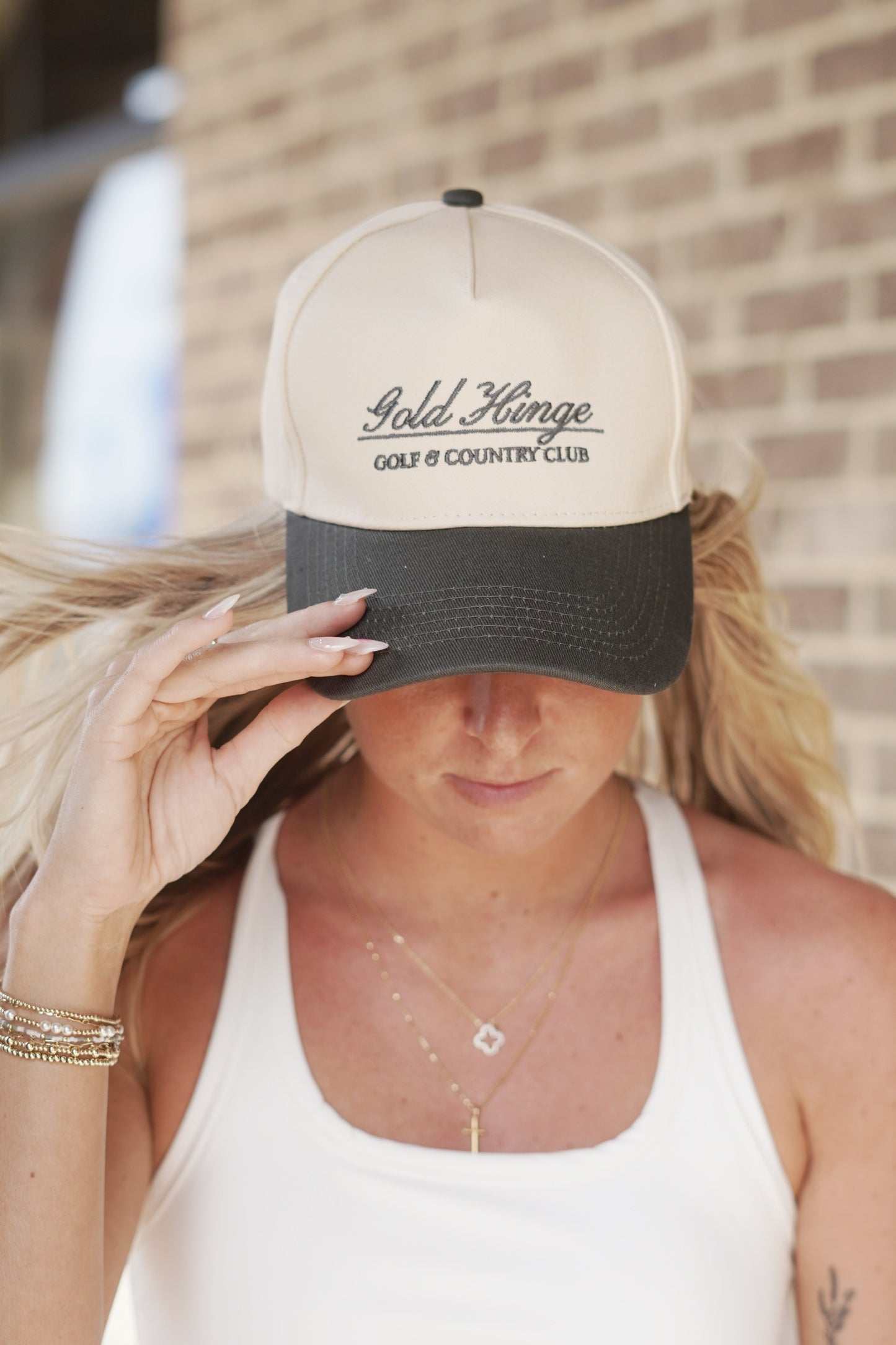 <ul> <li>Gold Hinge Country Club Hat</li> <li>"Gold Hinge Golf and Country Club" Lettering</li> <li>Trucker Hat Style</li> </ul> blue grey colored bill with a cream colored base hat