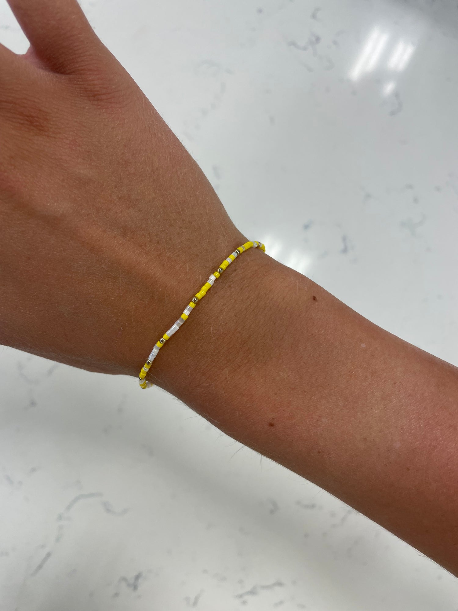 stretchy beaded bracelet with yellow, clear, white, and gold beads