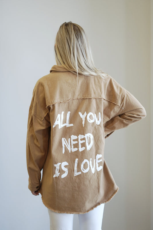 All You Need is Love Shacket Collared Neckline Long Cuffed Sleeves "All You Need is Love" in white lettering graphic on the back Color: Camel Oversized Length and Fit 100% Cotton