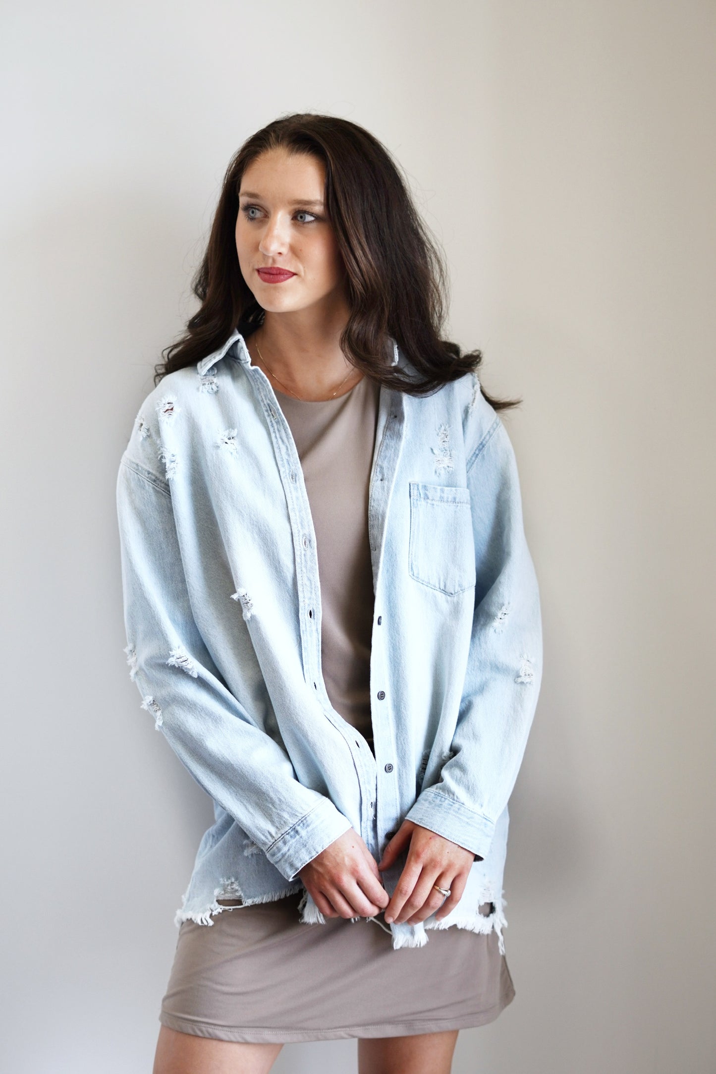 Darla Denim Distressed Shirt Collared Neckline Long Cuffed Sleeves Distressing Light Denim Color Front Left Pocket Fringed Hem Line Relaxed Fit Upper Thigh Length 100% Cotton Care: Turn inside out, Machine wash cold, Tumble dry low, Gentle cycle with like colors, Do not bleach, Hang to dry, Indigo will bleed, Iron if needed, 56