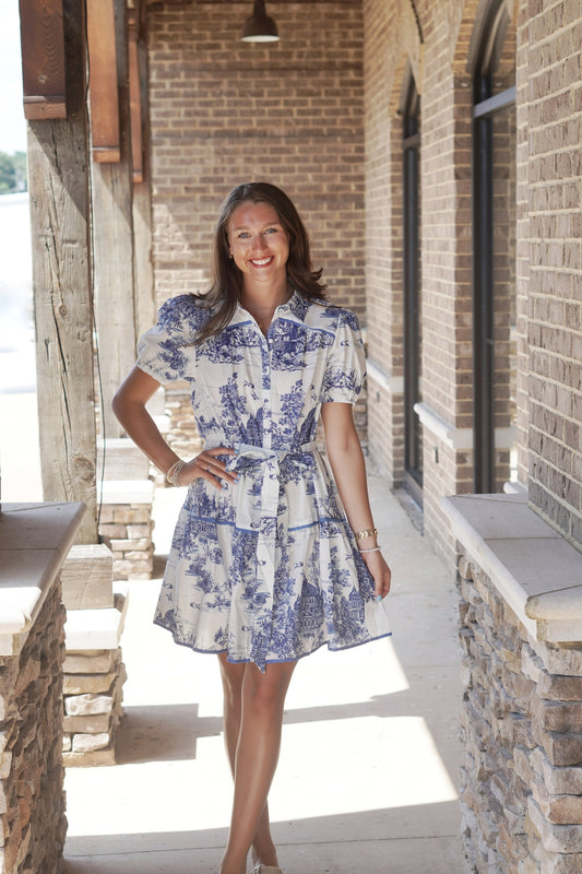 Meet Me for Brunch Puff Sleeve Dress Collared Neckline Short Puff Sleeves Waist Tie Button Down Feature Color: White w/ Blue Toile Print&nbsp; Mid-Thigh Length Blue Trim 100% Cotton