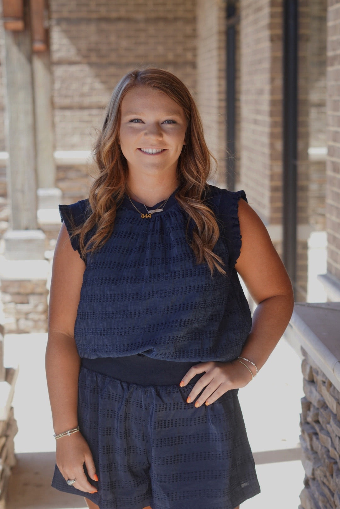 Naomi Navy Textured Top Crew Neckline Sleeveless Ruffle Detail on Hem of Arm Holes Color: Navy Textured Fabric Full Length Relaxed Fit 98% Polyester, 2% Spandex