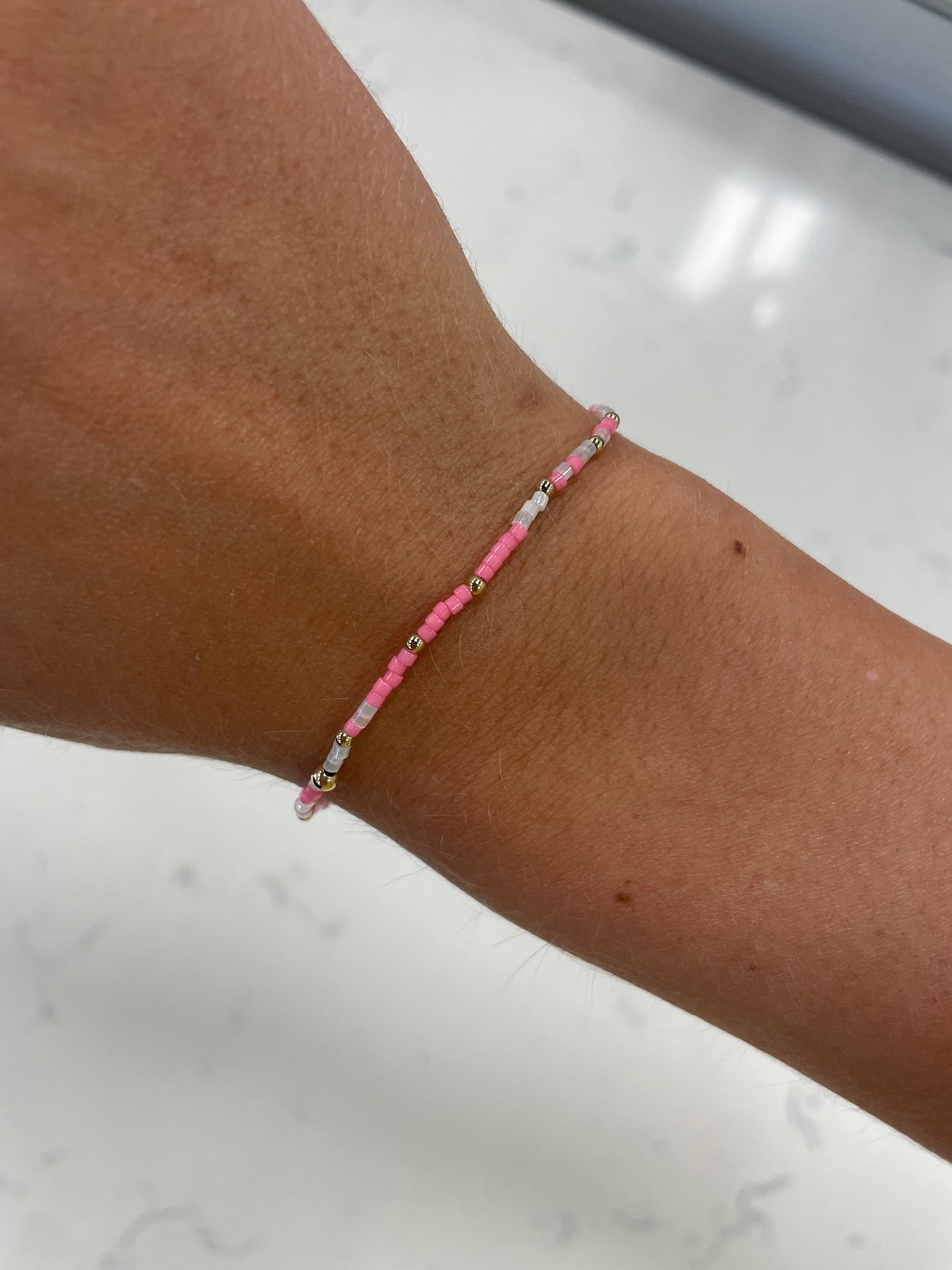 stretchy beaded bracelet with pink, white, clear, and gold beads