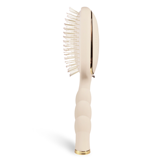 Oval hair brush, beige handle, gentle glide bristle, textured handle with gold trim shown from the side. 