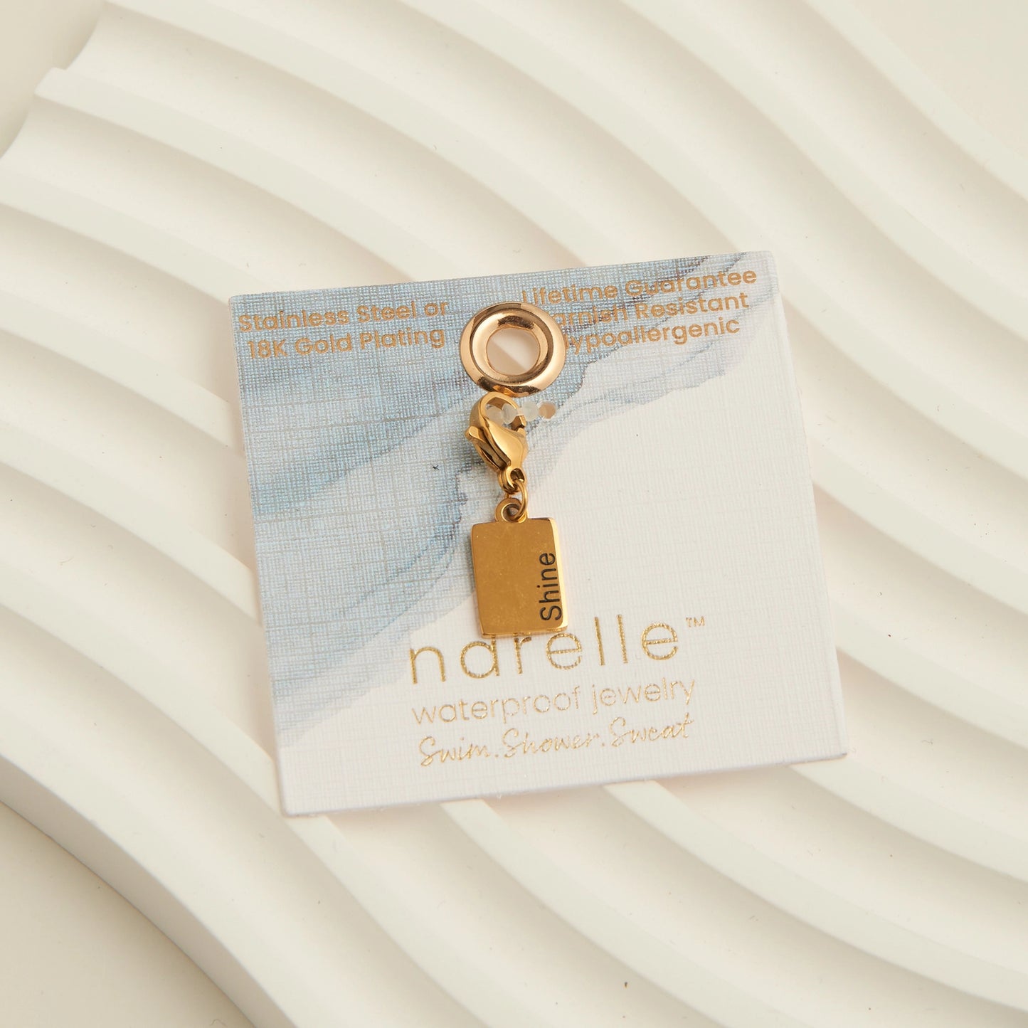 Gold rectangle charm with the word shine written,with a lobster clap. 