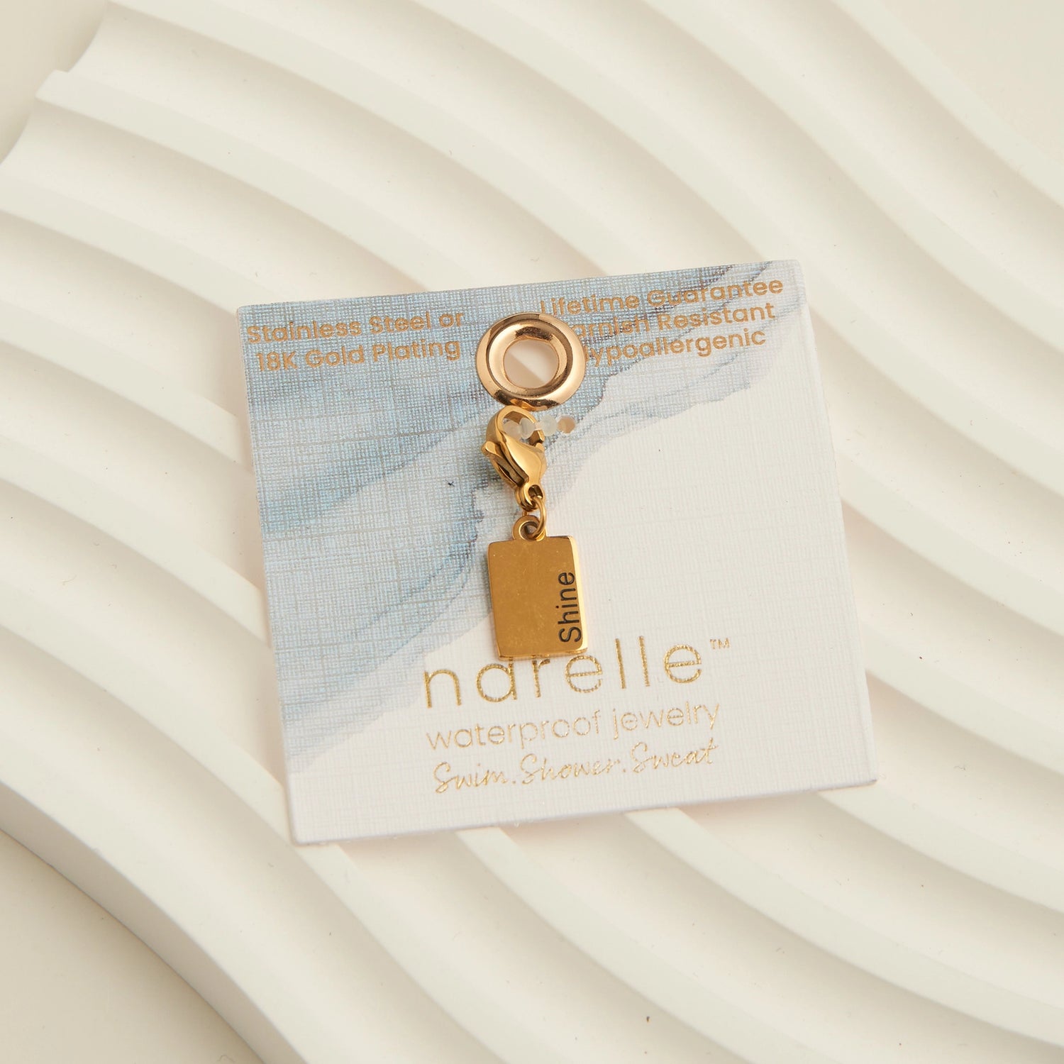 Gold rectangle charm with the word shine written,with a lobster clap. 