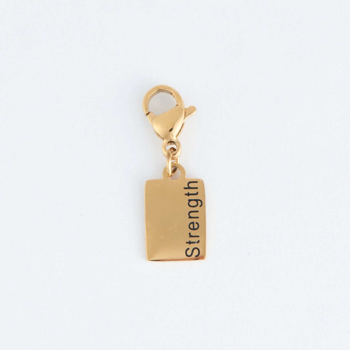 Gold rectangle charm with the word Strength  written, with a lobster clap. 