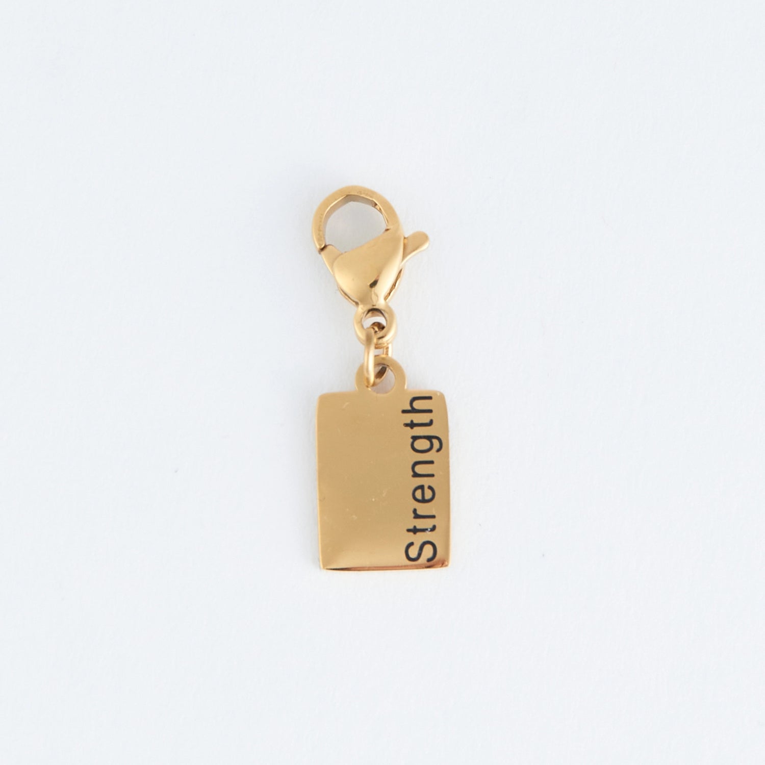 Gold rectangle charm with the word Strength  written, with a lobster clap. 