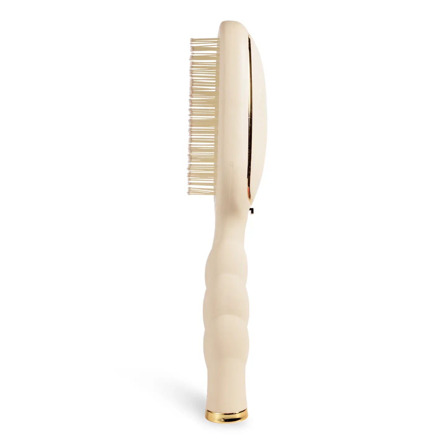 Side view of a oval beige hairbrush with an textured handle and gold trim.