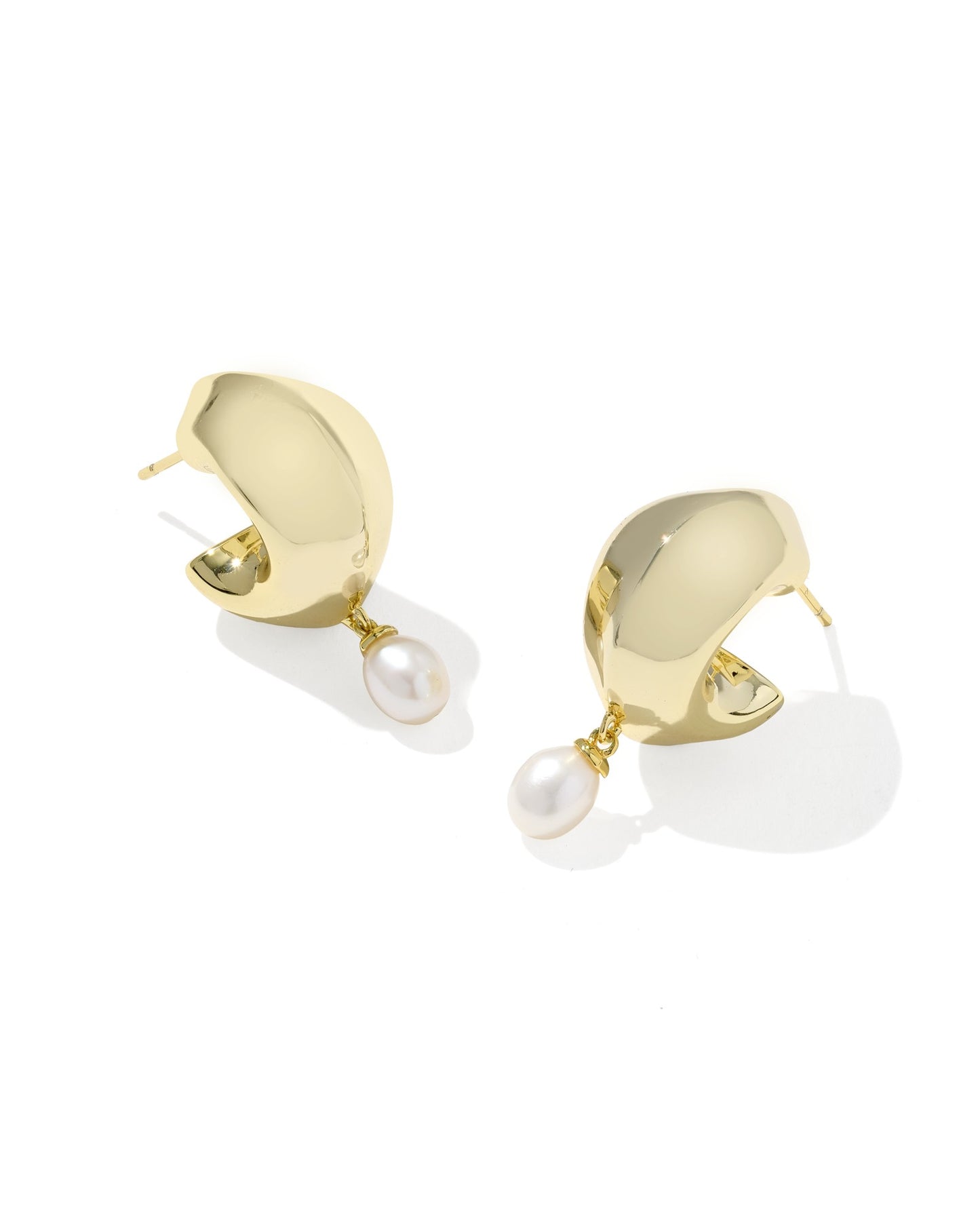 A pair of gold crescent-shaped hoop earrings with a dangling white pearl, shown on a clean white background.