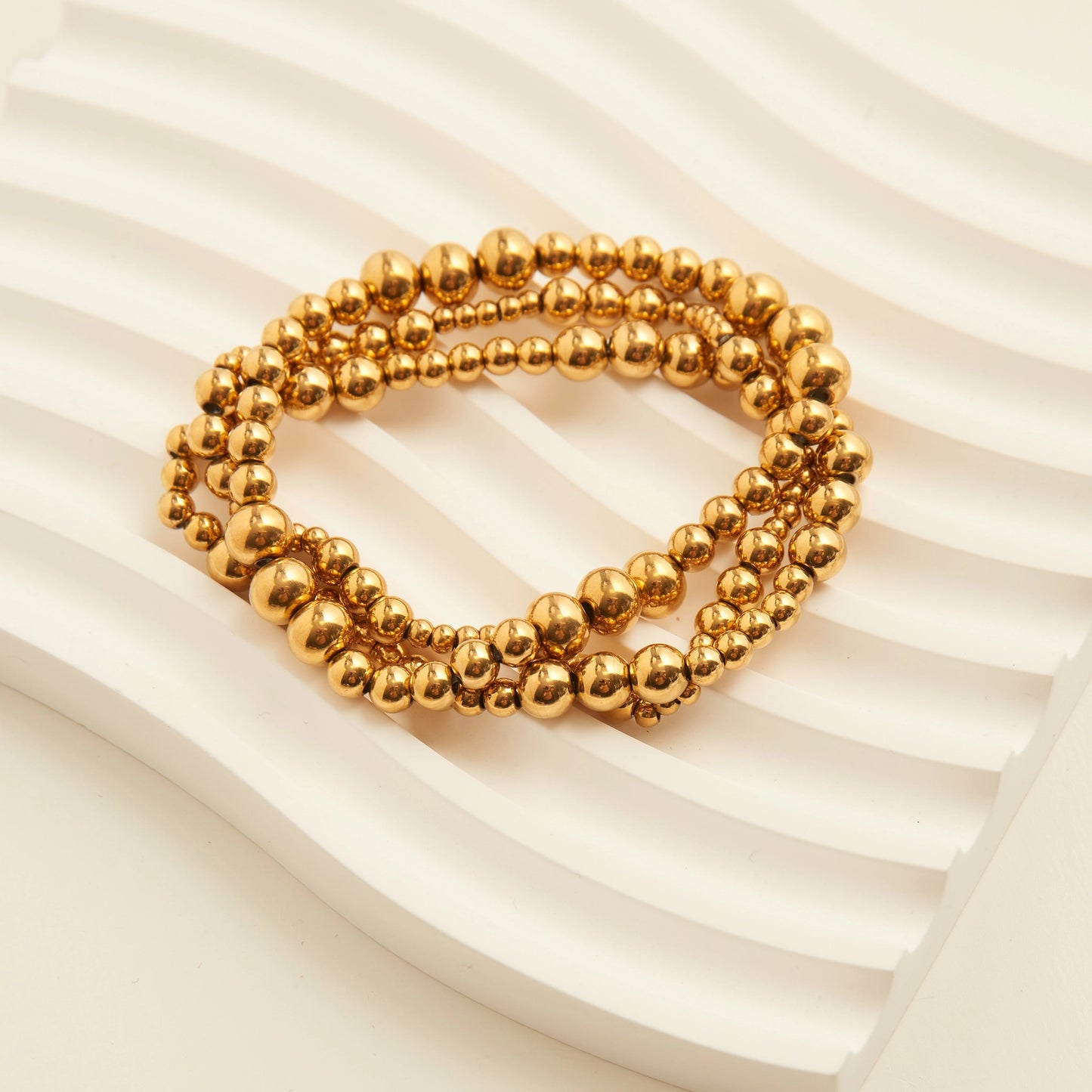  3-piece stack features stretch-fit beaded bracelets with graduated ball sizing in gold. 