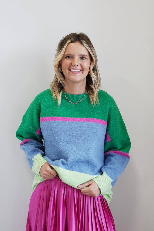 Cate Color Block Knitted Sweater Round Neckline Colors: Kelly Green, Lime Green, Pink, Blue Long Cuffed Sleeves Full Length Relaxed Fit 77% Acrylic, 20% Nylon, 3% Spandex